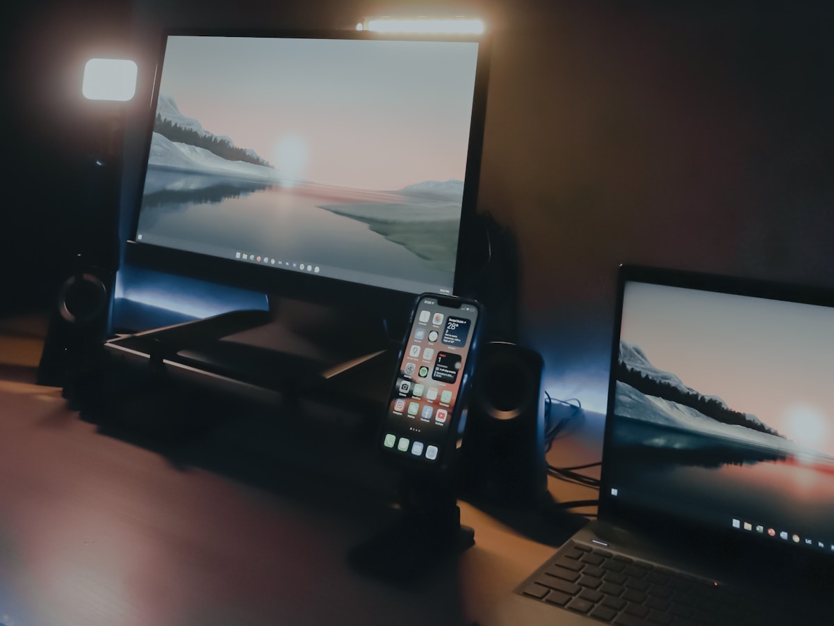 Desktop monitor, laptop, and smartphone in a home workspace.