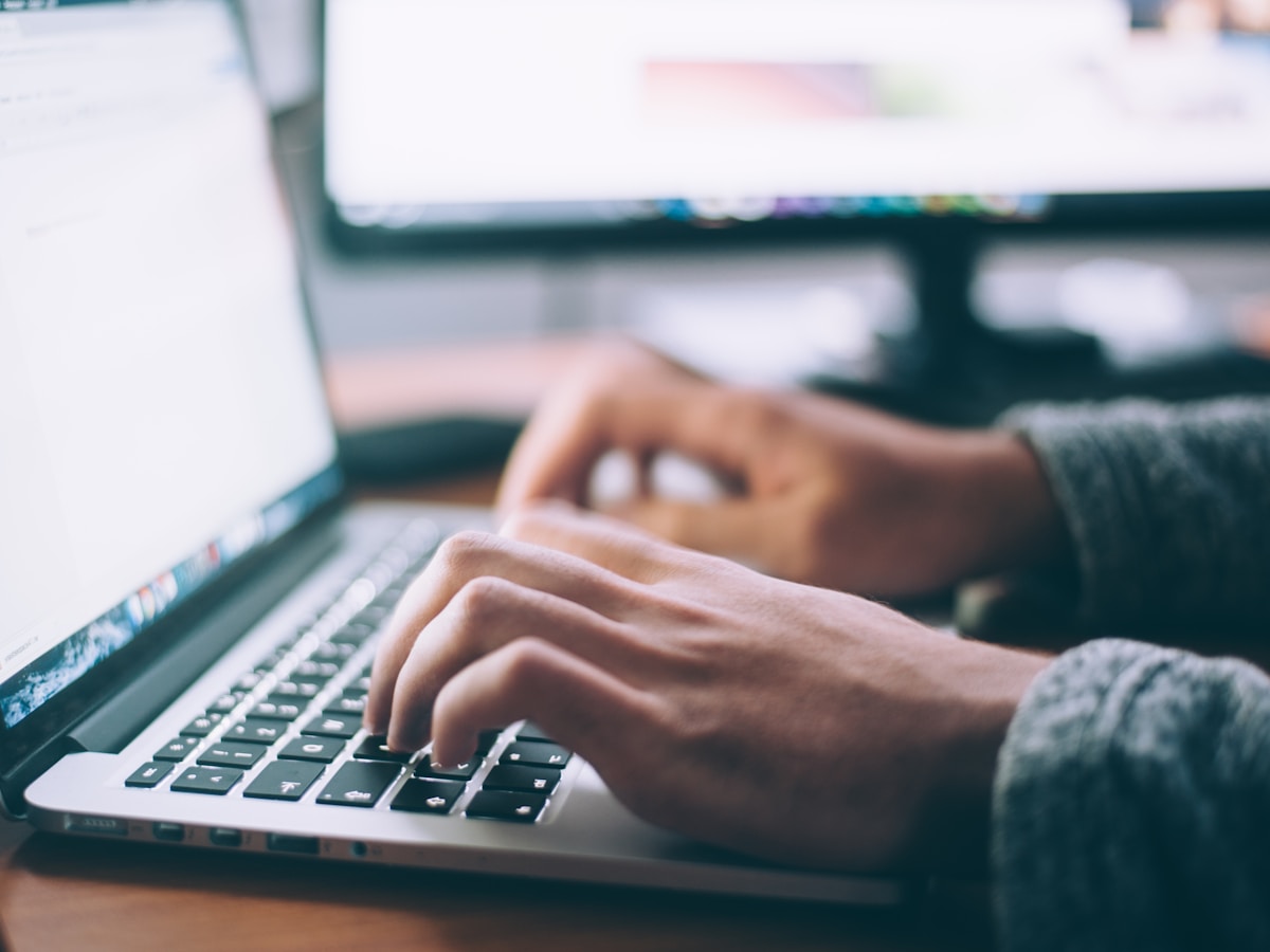 Hands typing on a laptop at a desk.